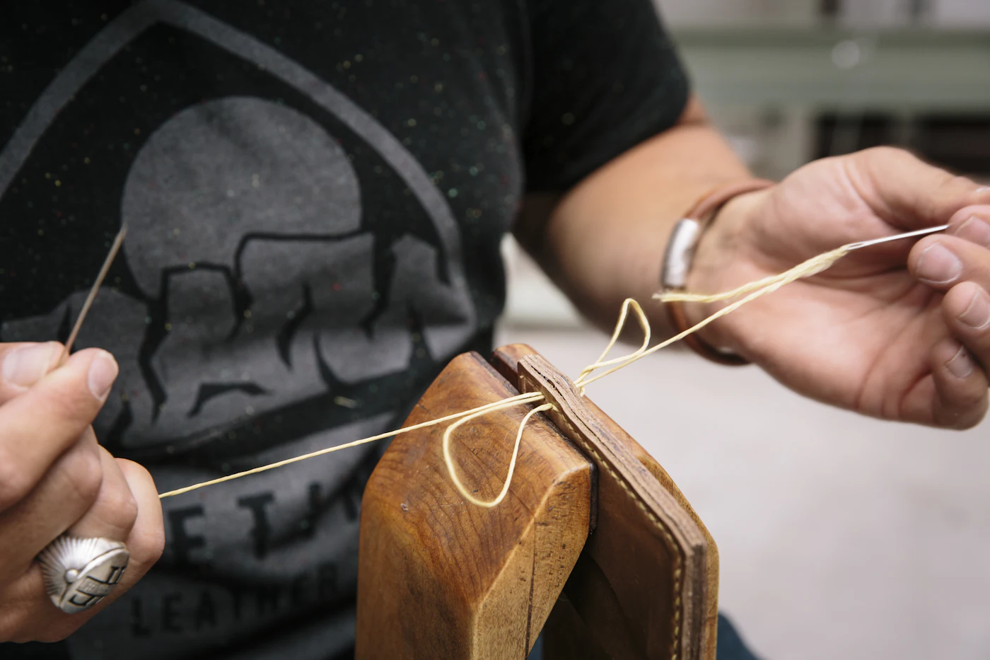 Craftsman saddle-stitching a leather piece by hand